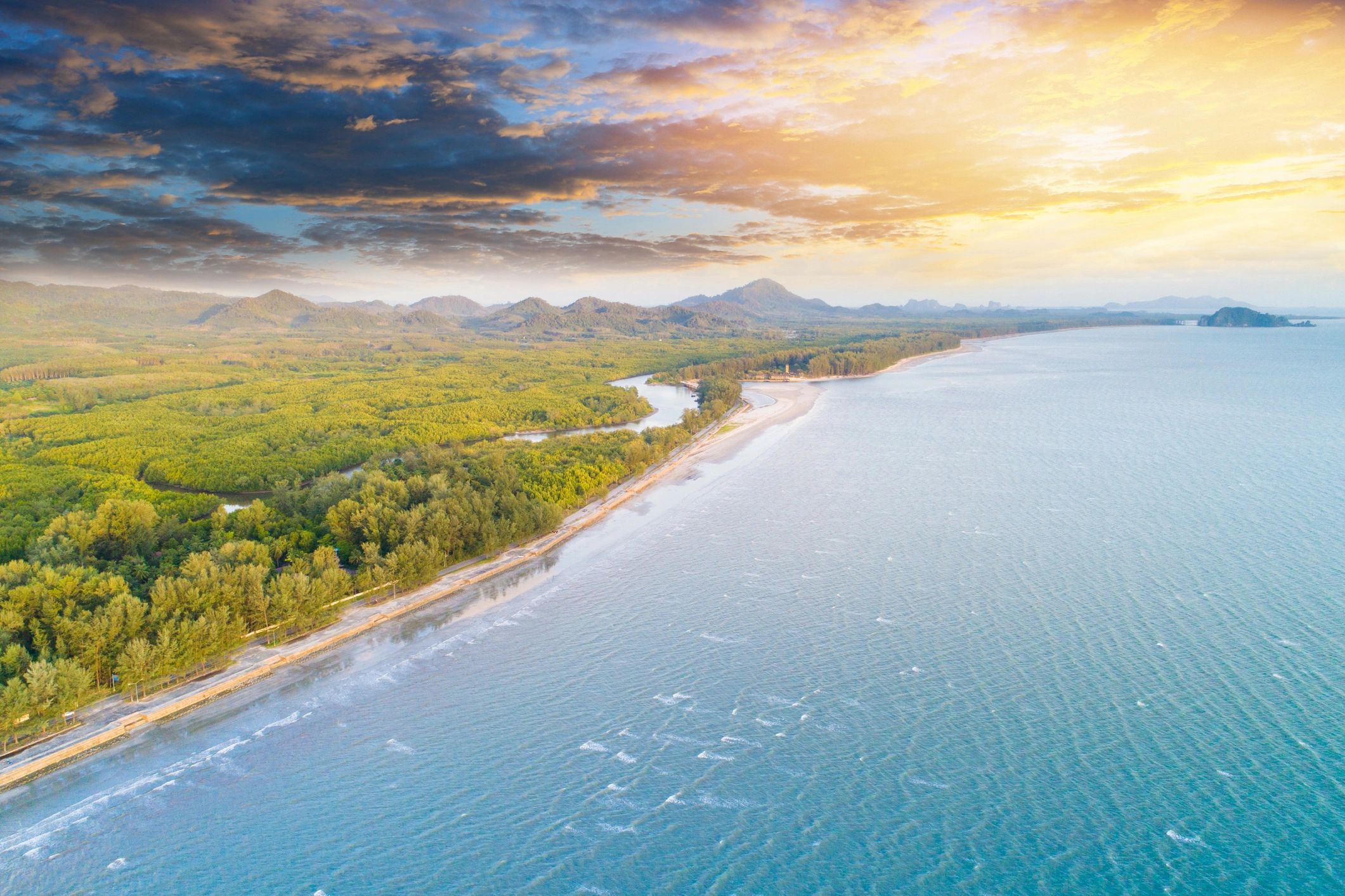 Wide tropical coastline with vivid blue water and warm sunset light